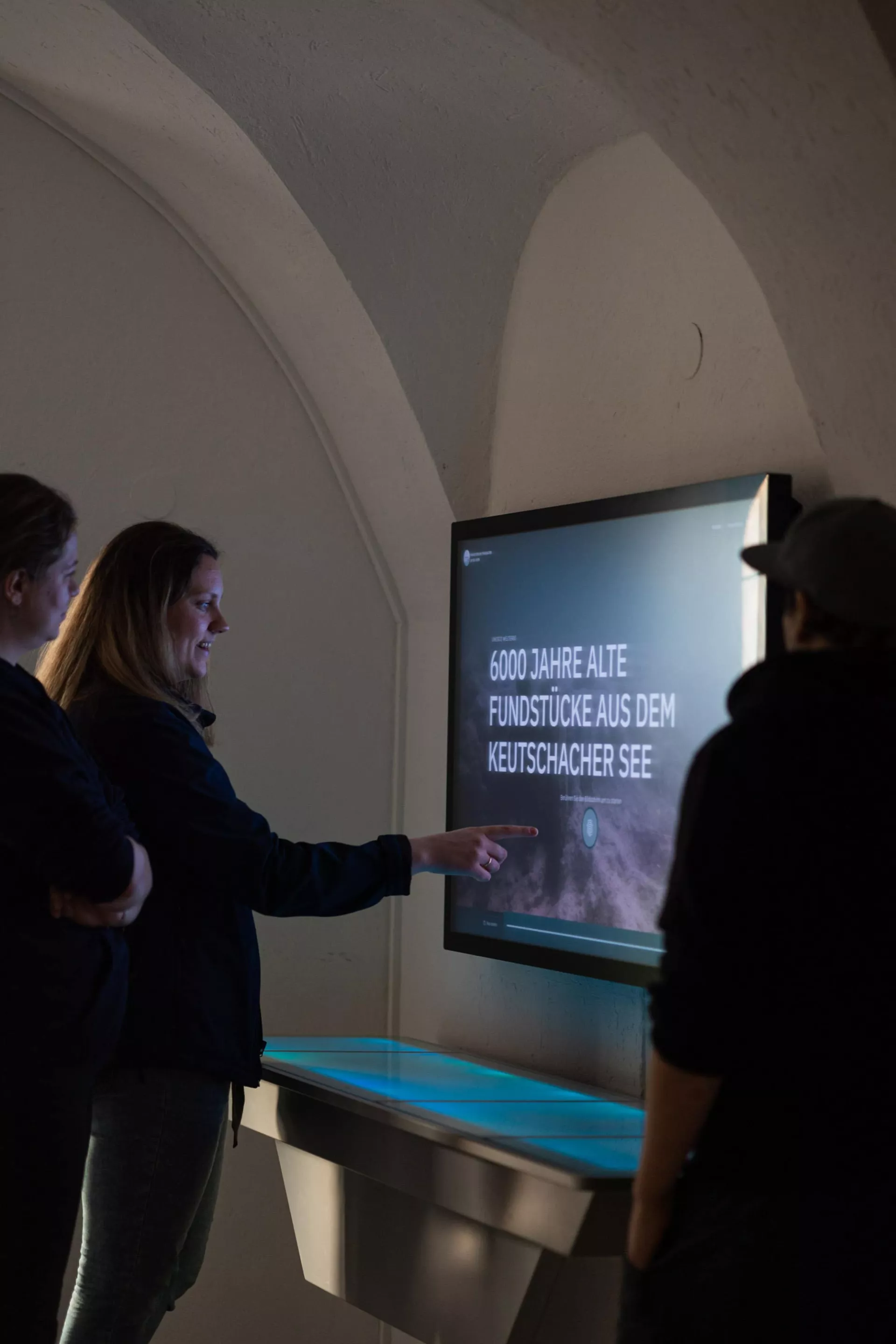 Frau bedient einen Touchscreen, der auf der Wand montiert ist.
