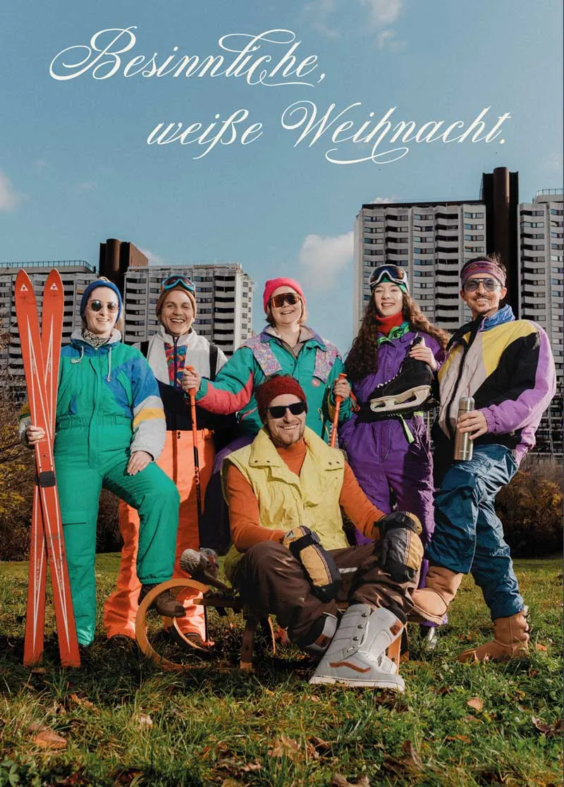 Lowfidelity Team in Vintage Kleidung auf einer grünen Wiese vor Alterlaa. Über den Personen steht Besinnliche, weiße Weihnacht.