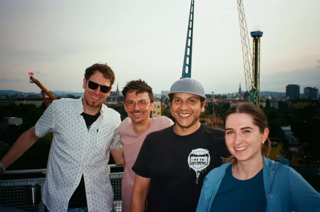 gruppe von vier personen lächeln in die kamera. drei männer und eine frau. im hintergrund der wiener prater