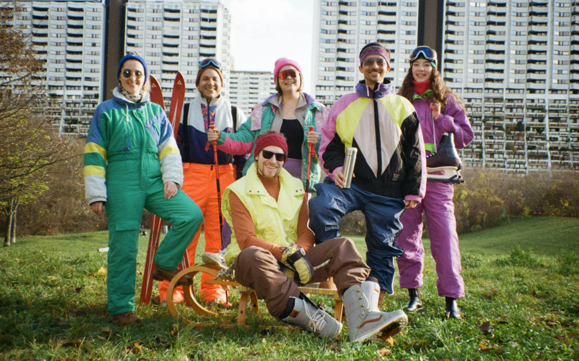 Lowfidelity Team in Vintage Kleidung auf einer grünen Wiese vor Alterlaa. Über den Personen steht Besinnliche, weiße Weihnacht.