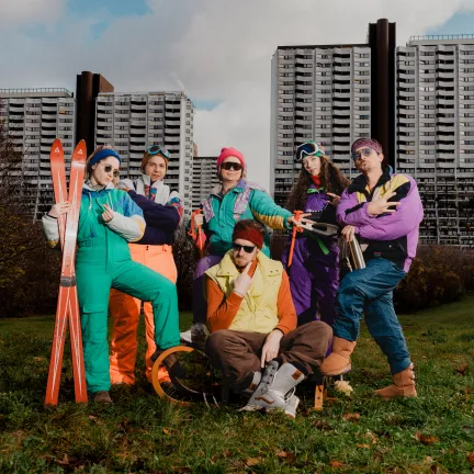 Lowfidelity Team sitzt auf einer grünen Wiese vor Alterlaa und zeigt Gang-Signs