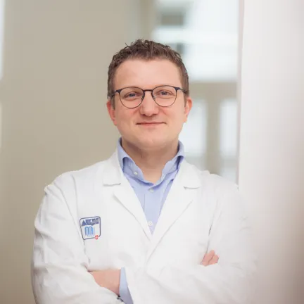 Portrait von Kevin Staats, er lehnt mit verschränkten Armen an einer Tür